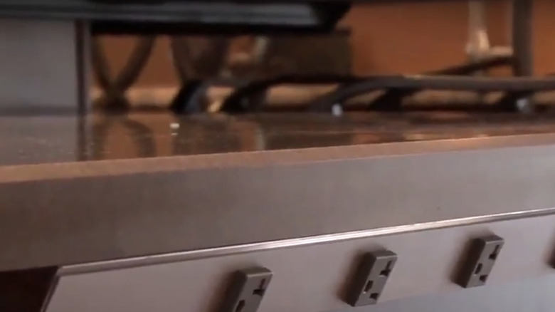 An outlet strip below the second tier of a kitchen island