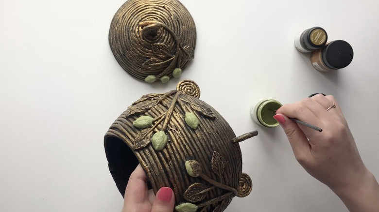 A coiled paper jewelry box painted with black glitter paint