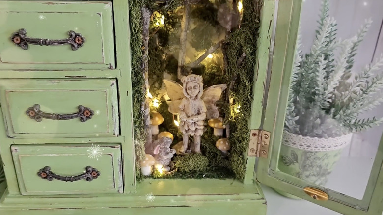 An upcycled jewelry box with fairy lights and moss design elements