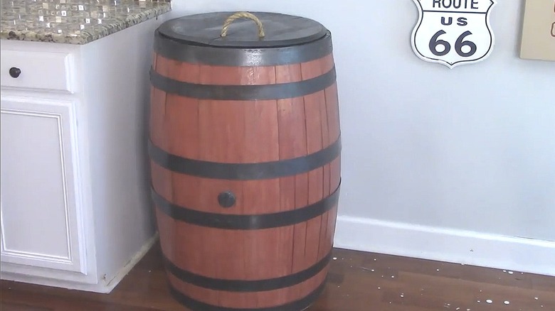 Refinished wood whiskey barrel in a kitchen serving as a trash can