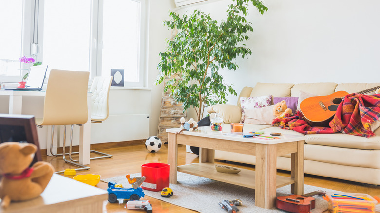 A messy living room with clutter on the floor.