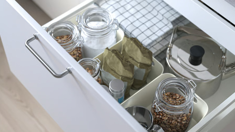 White, plastic UPPDATERA boxes in a kitchen drawer with coffee, and other products inside