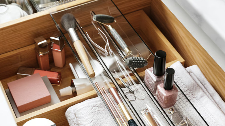 The VISSLAÅN drawer organizer on top of other products in a drawer holding brushes, nail clippers, nail polish, and jewelry