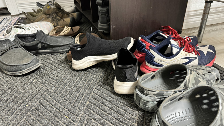 Cluttered shoes near a shoe shelf