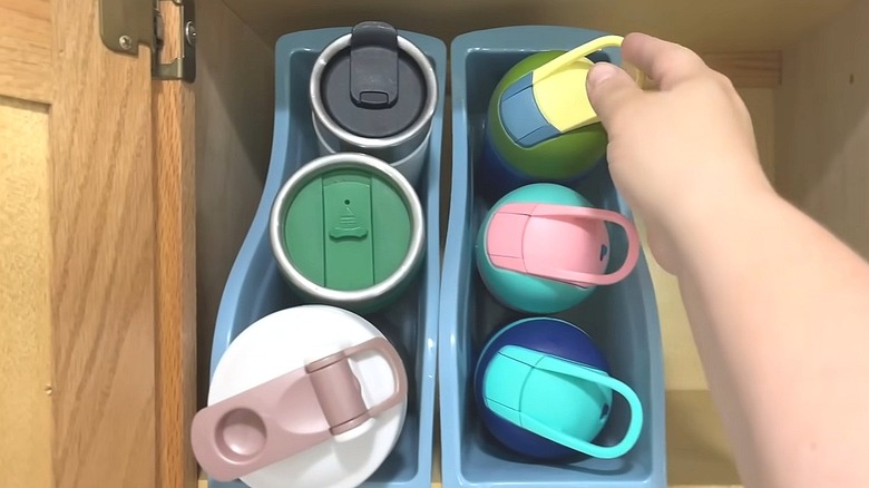 Person reaching for a water bottle stored in a Dollar Tree book bin
