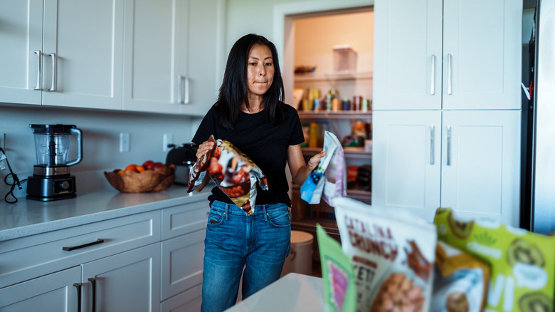Woman removing bags of dry goods from pantry in modern kitchen