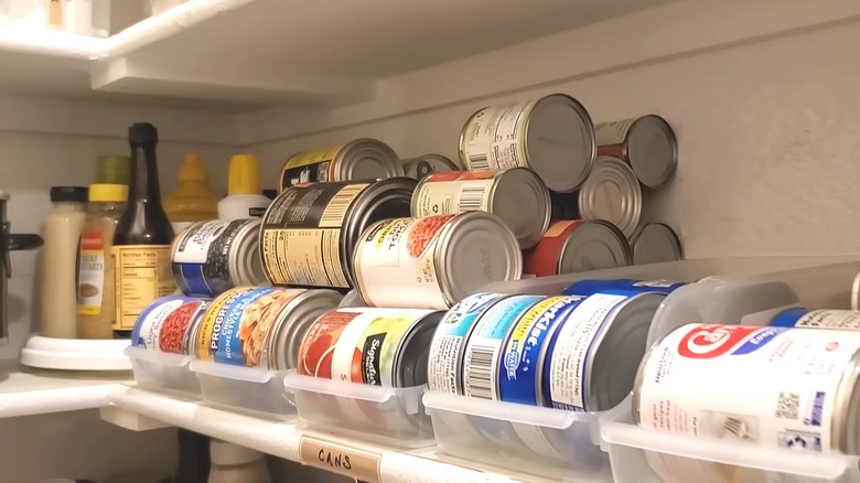 Pantry shelves lined with Dollar Tree soda can holders filled with canned goods