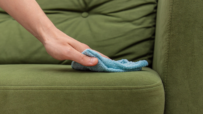 person wiping down couch seat with microfiber cloth