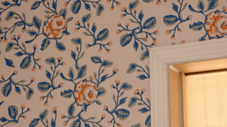 Hand-painted wallpaper with peach flowers and blue and green leaves by HGTV designer Erin Napier on a wall near a door frame.