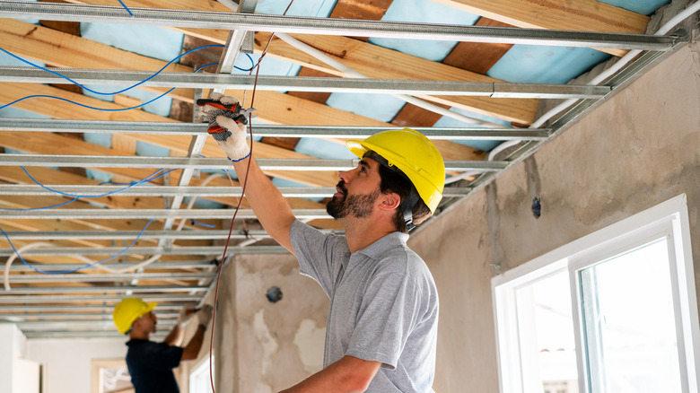 Contractors installing ceiling grid track system in home