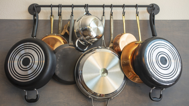 Kitchen pans hung via S-hooks from a wall-mounted rack