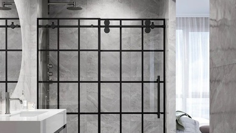 A white subway-tiled bathroom with a frameless sliding glass door installed on a silver track with wheels at the top