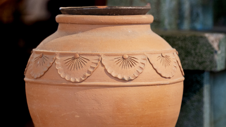 A close up on a terracotta pot with a lid