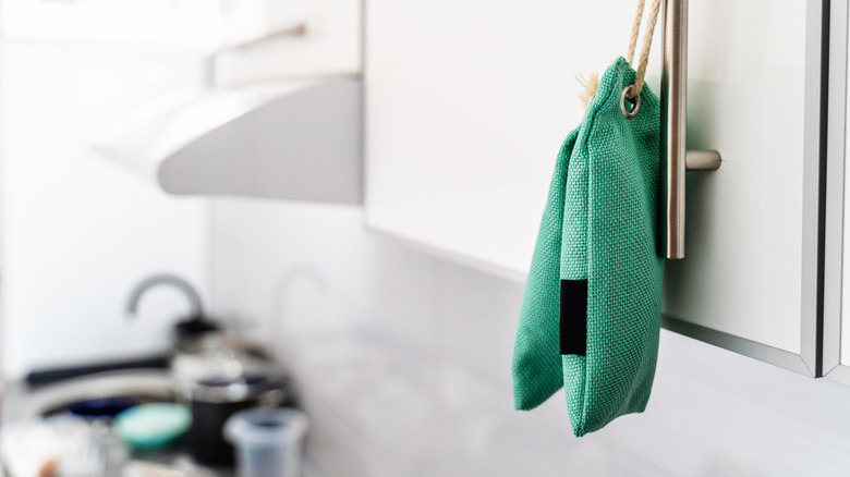 Green bags hanging from a kitchen cabinet door from string