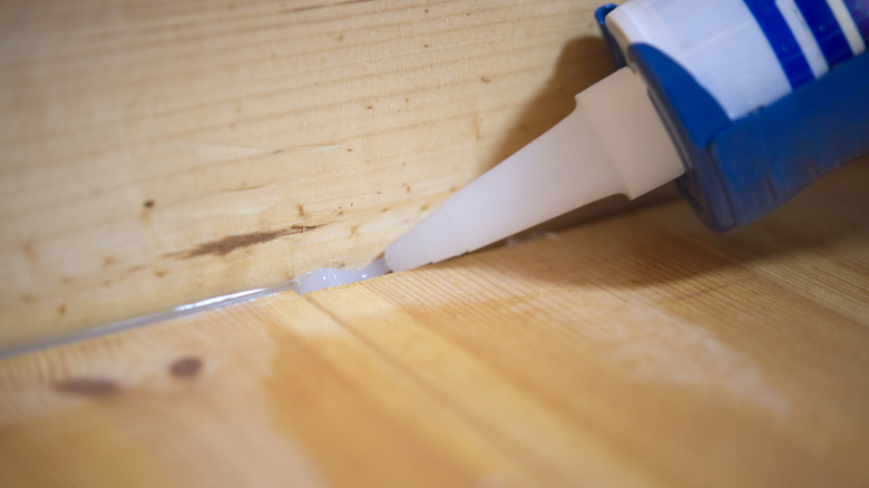 Close-up of adhesive being applied to a wooden surface