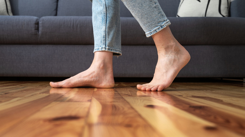 Close-up of a barefoot woman stepping on a hardwood floor