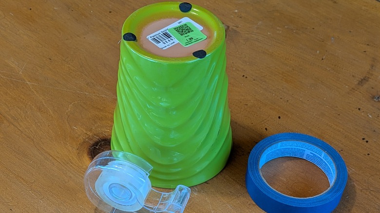 An upside-down flower pot and rolls of tape on a wood table