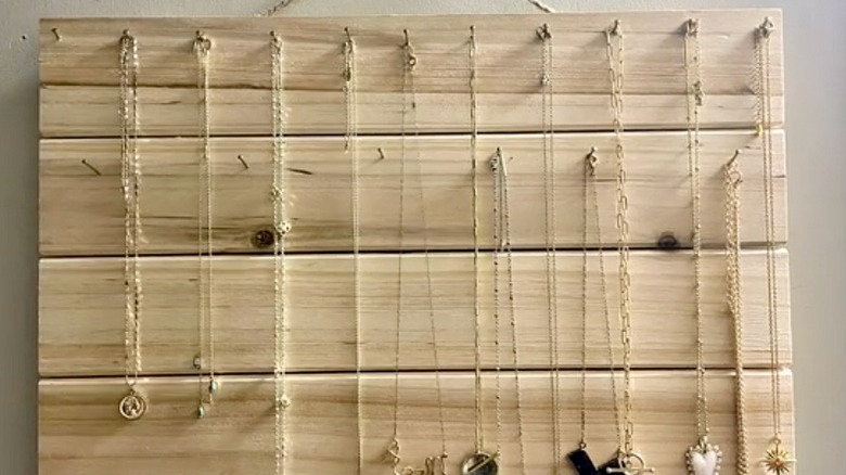 Closeup of wood board and nails with hanging necklaces