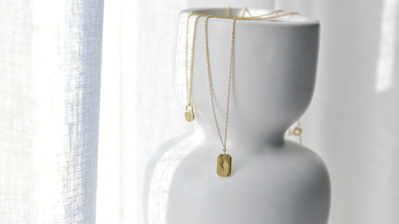 Closeup of a white vase with necklaces hanging from the top