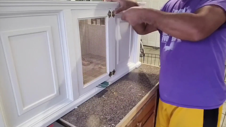 A man puts the finishing touches on a bench and crate combination for his small dog