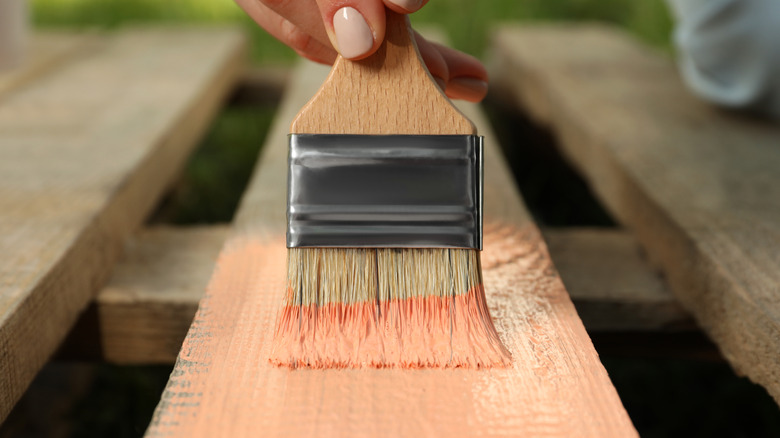 Person painting a wooden pallet