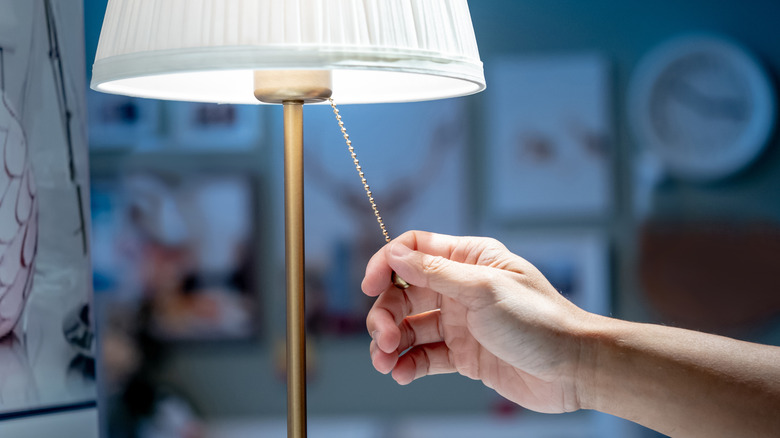 Hand pulling on a pull switch on a lit lamp