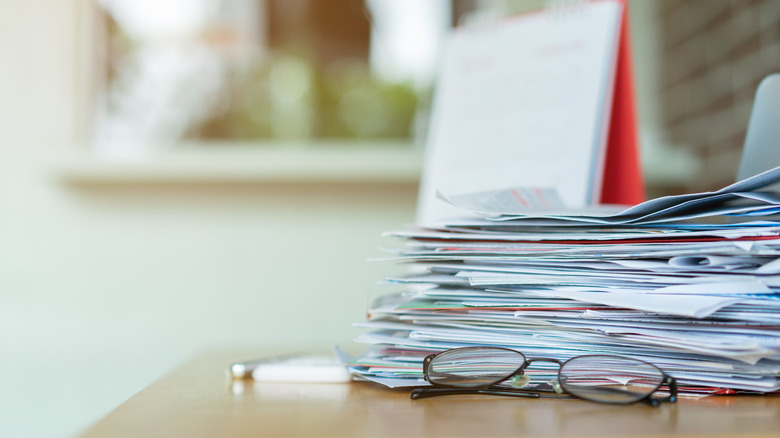 A stack of mail and documents with glasses in front.