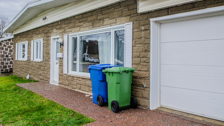 Two trash cans in front of stone house