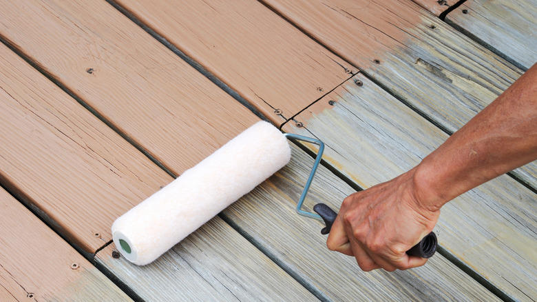 A man using a roller on a deck