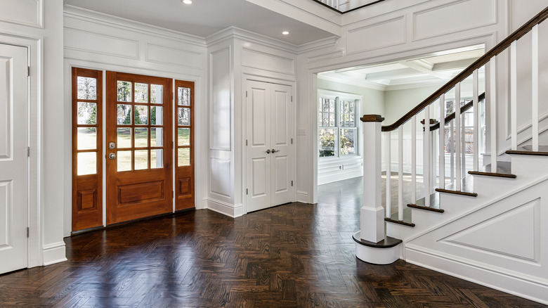 White home entryway with raised panel walls and closet doors