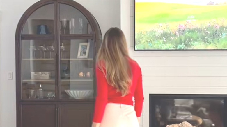 Woman walking towards armoire with bar drinks and glasses inside