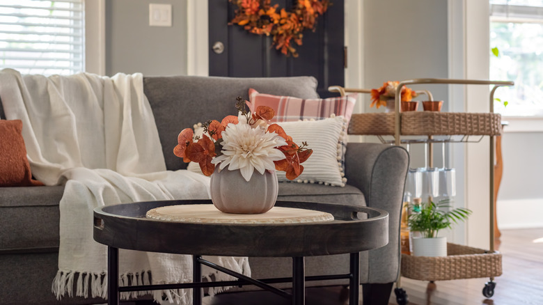 Wicker bar cart with glasses on it beside sofa in living room