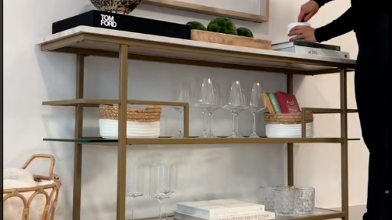 Person preparing a drink on top of a console table used as home bar setup