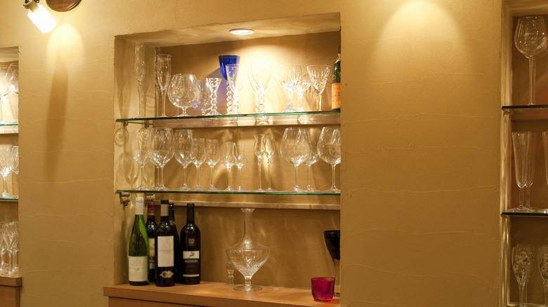 Built-in home bar nook with shelves filled with glasses and bottles