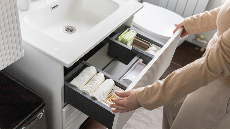 A woman organizing a bathroom drawer