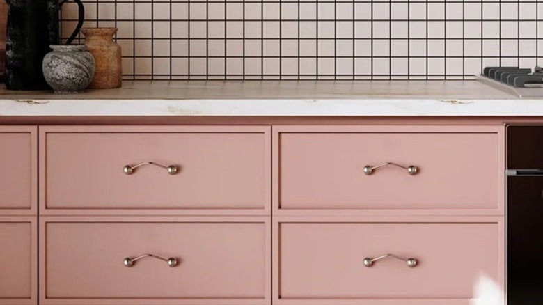 Wavy metal cabinet pull on pink lower cabinets