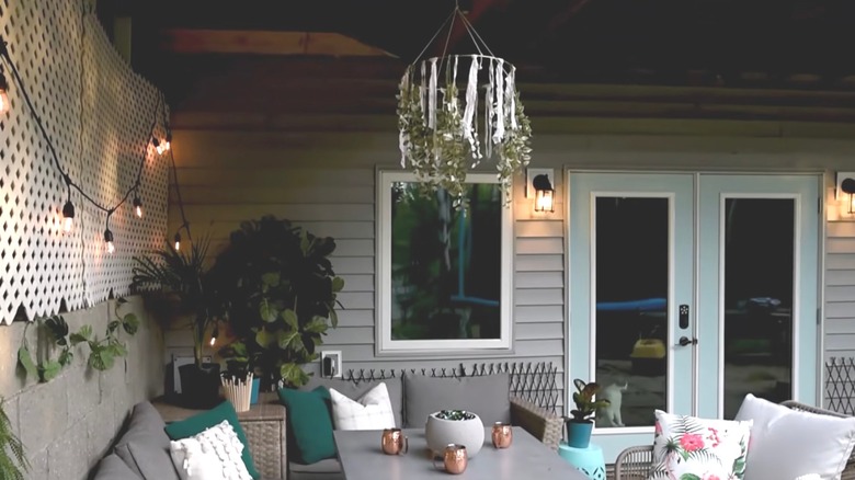 A mosquito-repelling fabric chandelier hangs in an outdoor patio space