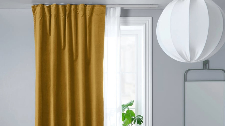Mustard curtains mounted on ceiling tracks in a room in a home.