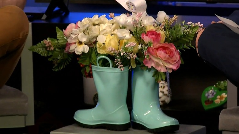 Green rubber boots filled with florals and ribbons tied around the top