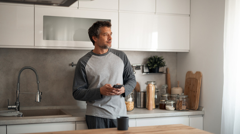 man stands beside cluttered countertop