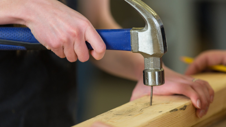 Person hammering a nail into a board