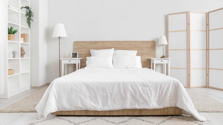 interior of bedroom with white walls and bedding and shelving unit