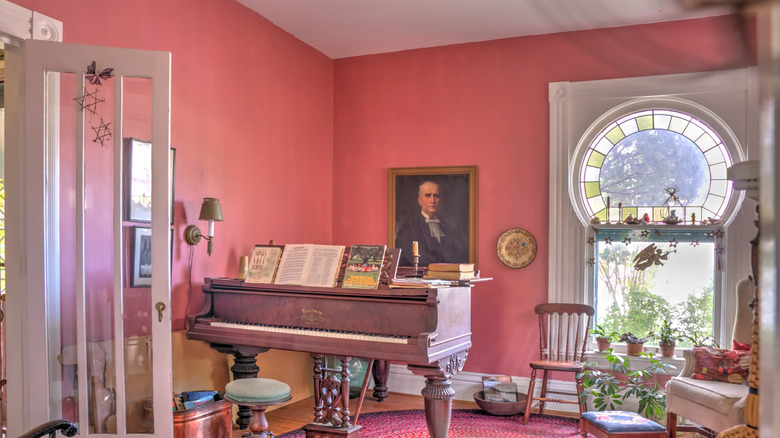 Sunny room with piano and rose pink walls.