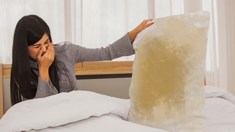 woman holding pillow with yellow stains 