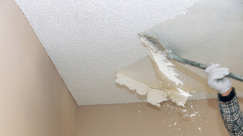 A man removing a popcorn ceiling with a scraper
