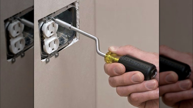 Person using a Rapi-Driv screwdriver on an electrical outlet