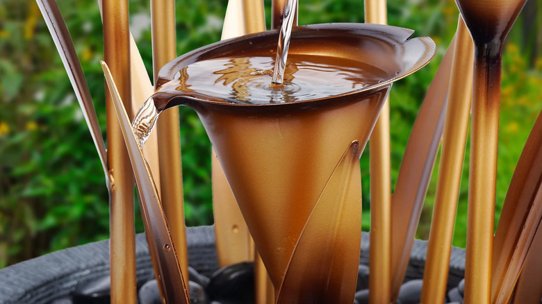 A closeup photo of a functioning calla lily water fountain in a yard