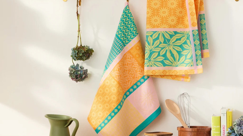 Two colorful hand towels hang in the kitchen above cookbooks and baking tools which sit on a counter