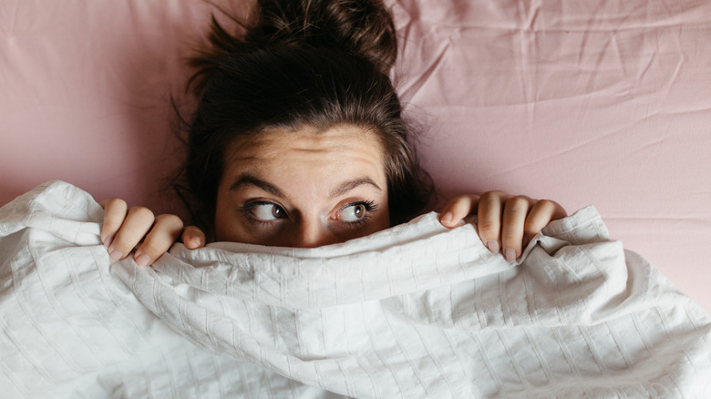 woman hiding under blanket