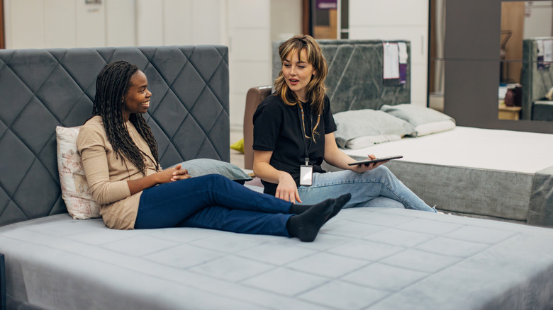 A customer shopping for a new mattress and chatting to the salesperson